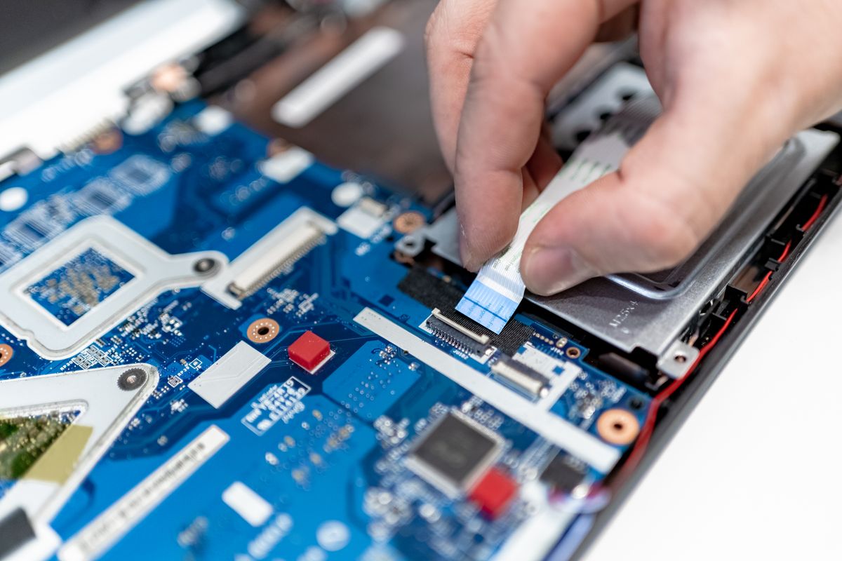 Close-up of a technician's hands carefully repairing a laptop circuit board