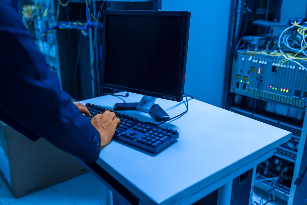 An IT technician working hands-on in a server room, monitoring and maintaining equipment